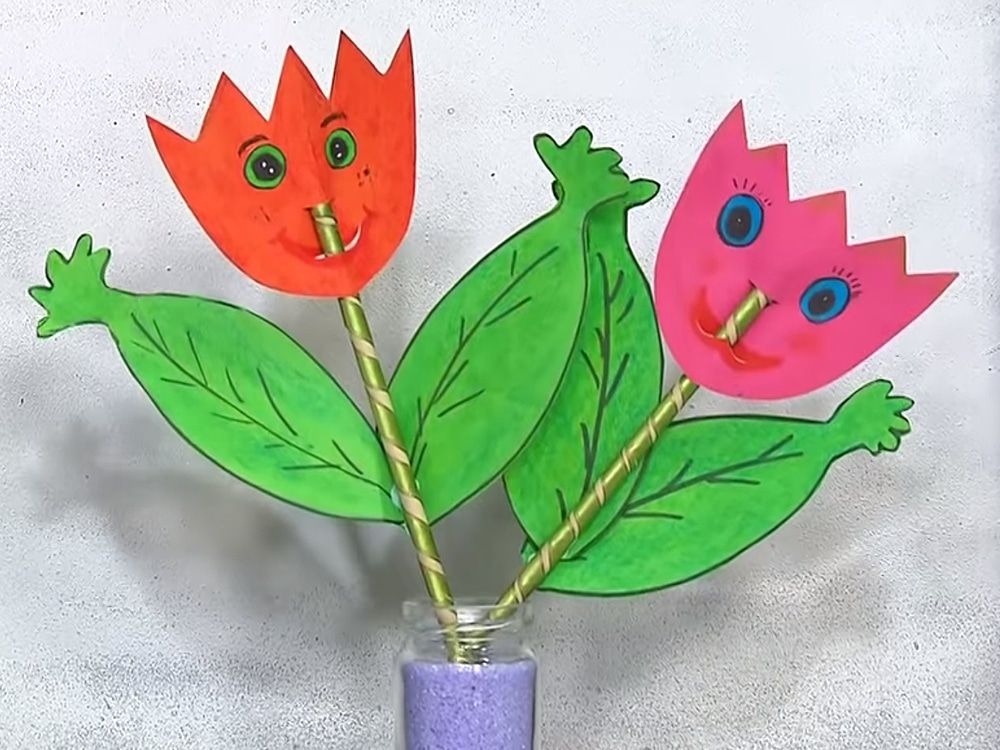 Gözlü, gülümseyen turuncu ve pembe kağıt laleler, pipet saplarıyla mor kum dolu kavanozda
