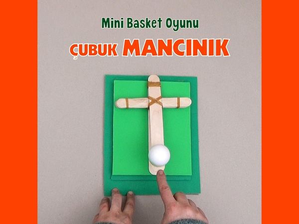 Mini basket oyunu için çubuk mancınık: yeşil kartona tutturulmuş dondurma çubukları ve üzerinde beyaz top