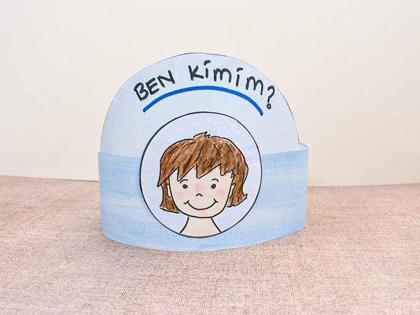 Ben Kimim? kağıt taç: mavi boyalı şerit üstünde başlık yazısı ve daire içinde çizilmiş çocuk yüzü